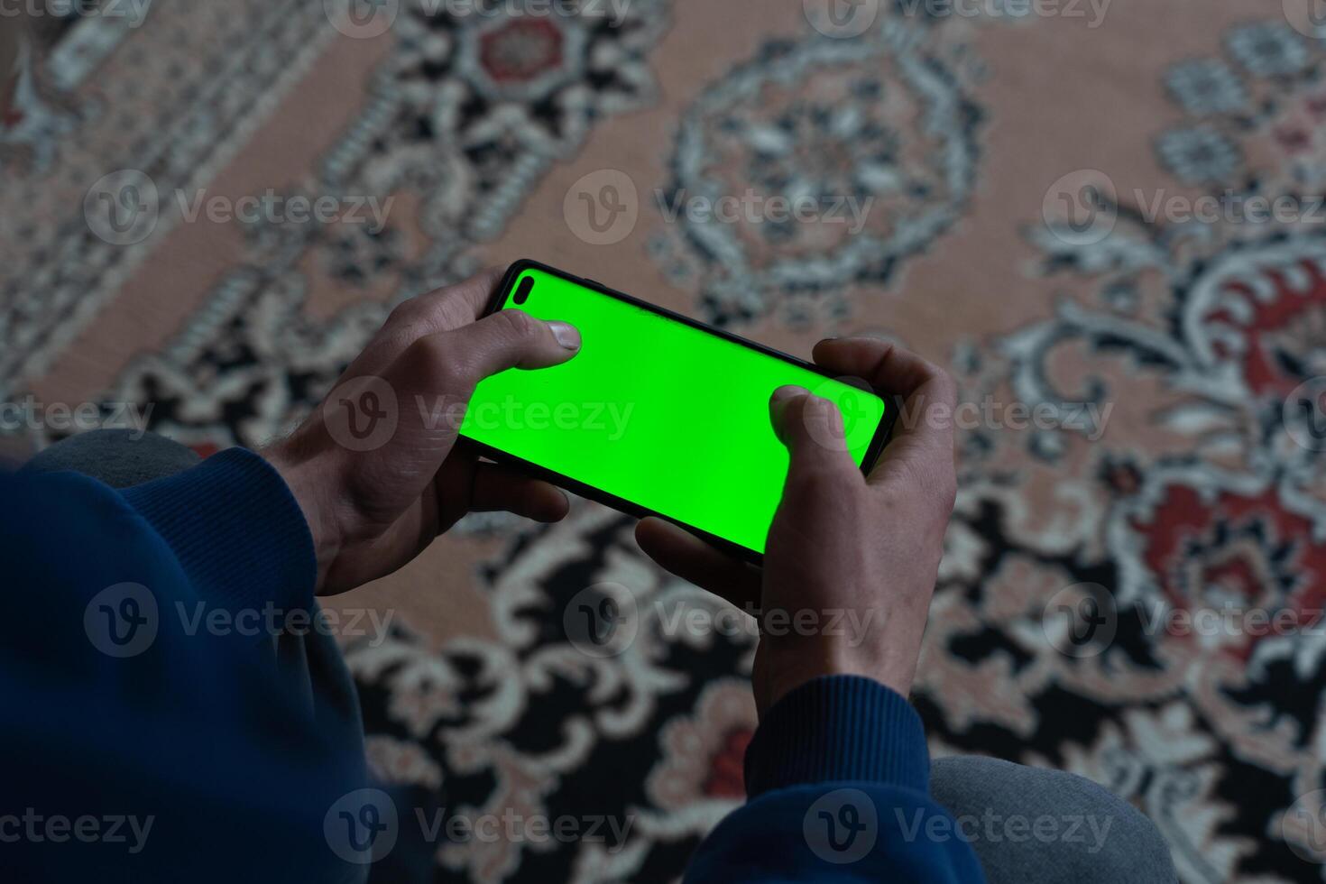 Guy with a smartphone in his hands with the green screen turned on photo
