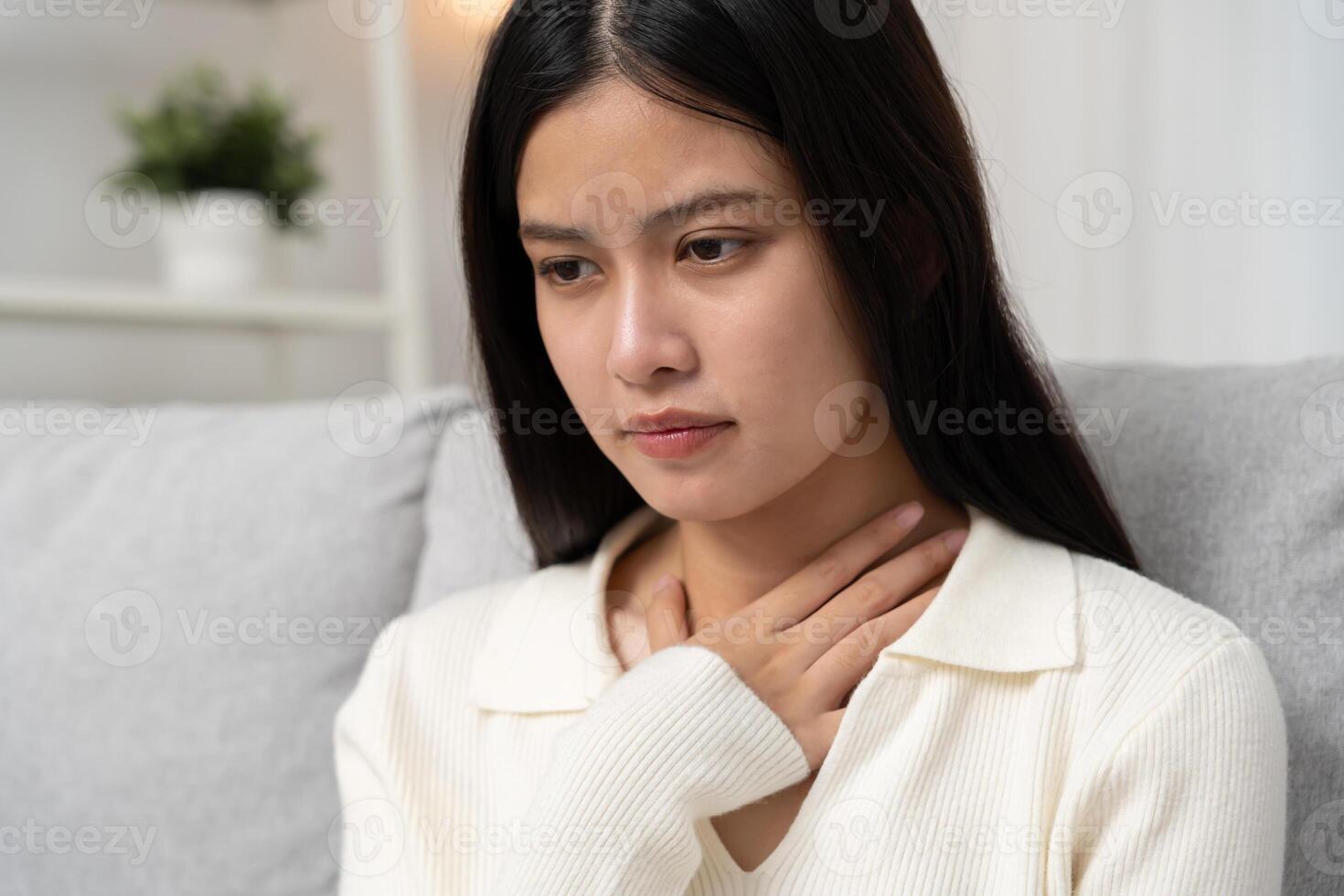 Asian woman put on neck due to a sore throat. female tonsillitis causes a inflammation. treated by taking water, taking antibiotics, consult a doctor, virus corona virus, Influenza. photo