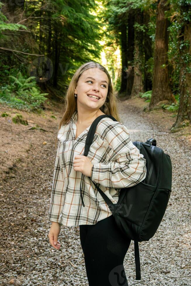 A Young Hiker Smiling Happily While Enjoying a Beautiful Forest Trail in Natures Embrace photo