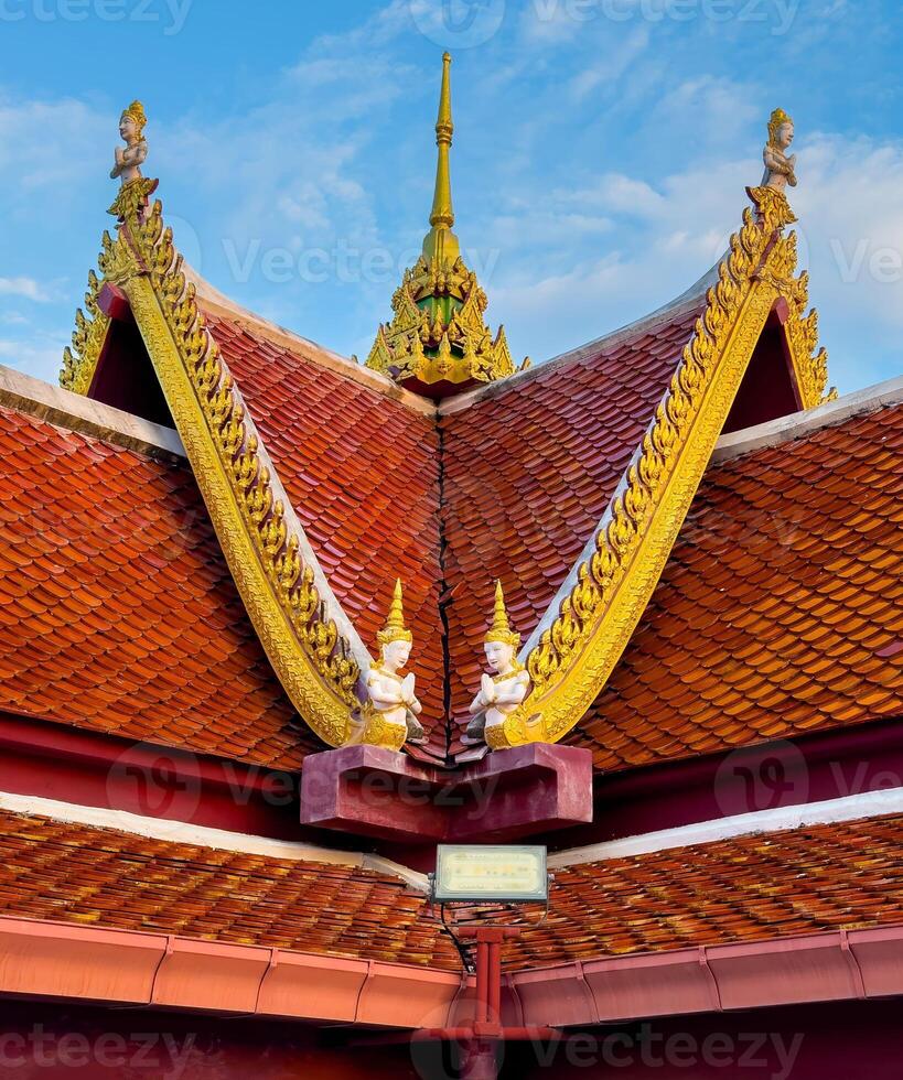 Captured from a low-angle perspective, this shot highlights the striking symmetry and vibrant colors of a traditional Thai temple roof. The rich, terracotta-colored tiles are beautifully complemented photo