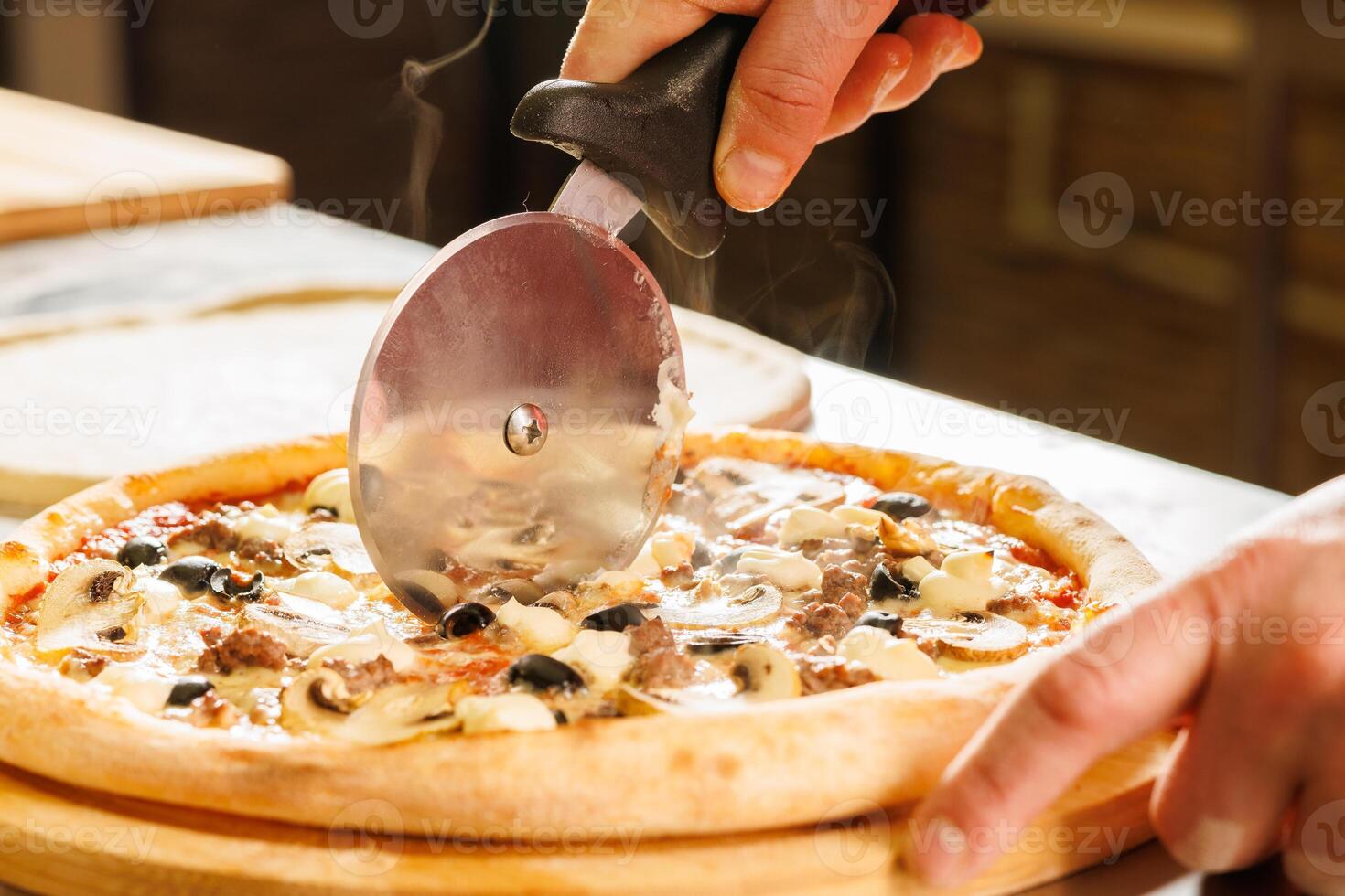 Cutting a freshly baked pizza with a pizza cutter photo