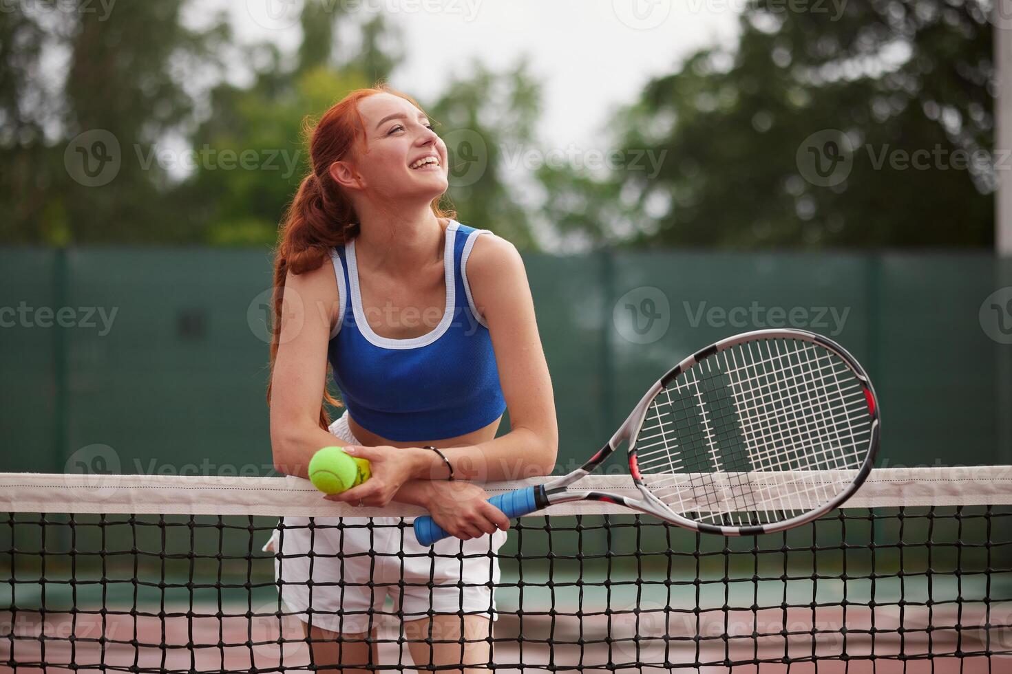 Smiling girl with tennis racket at net photo