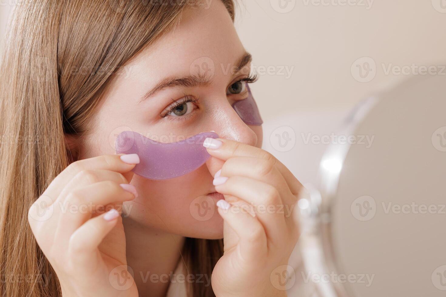Woman uses purple under-eye patches for hydration, de-puffing, and skin rejuvenation, highlighting a modern beauty and skincare routine. photo