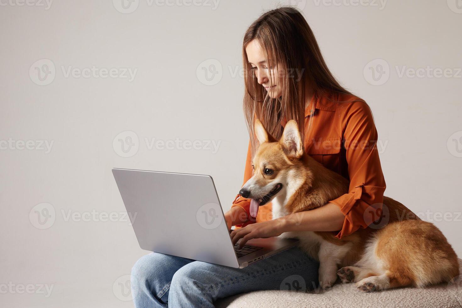 Woman working on laptop with Corgi dog on lap, cozy remote work lifestyle. photo