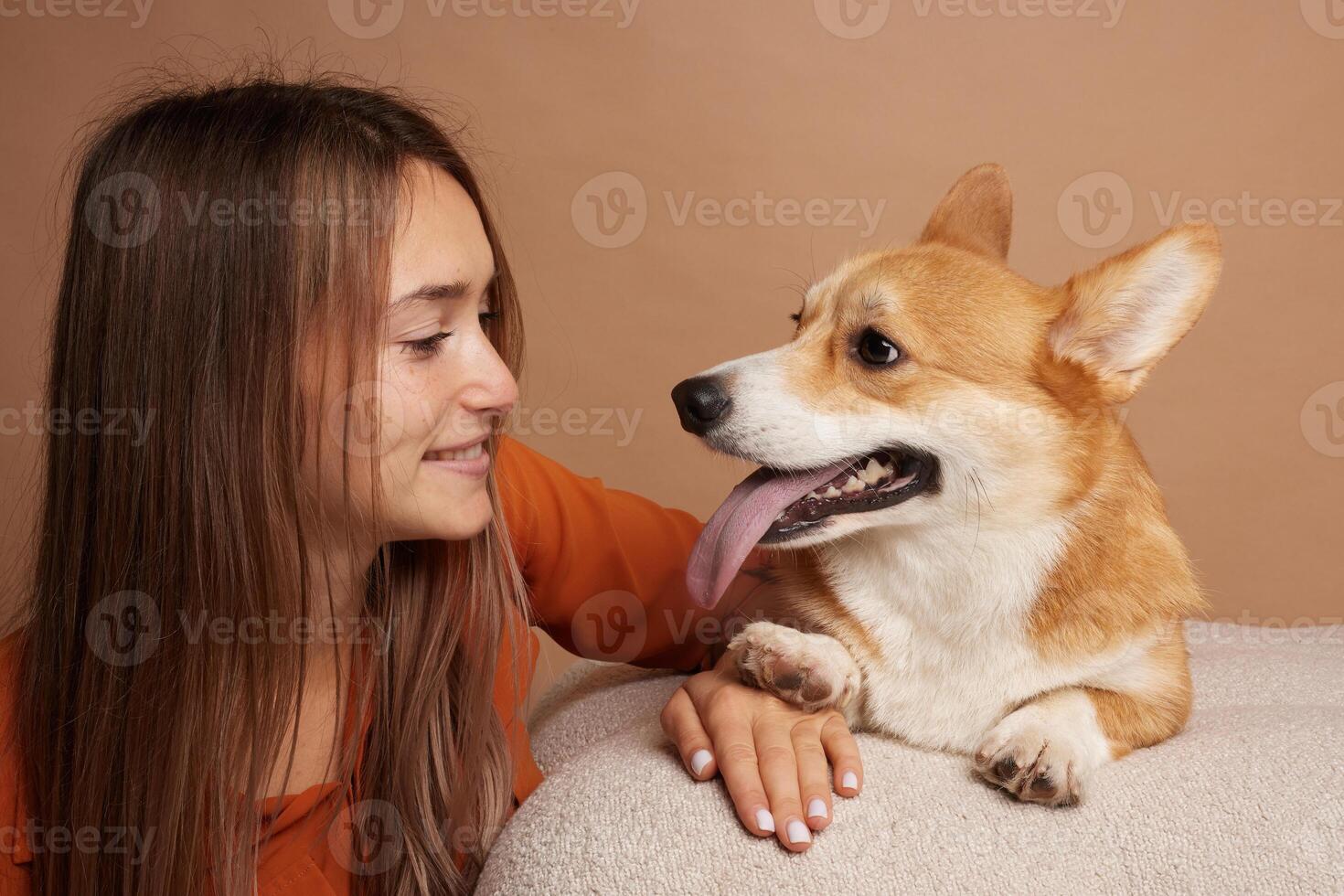 Woman smiling at Corgi dog with tongue out, playful and happy indoor moment. photo
