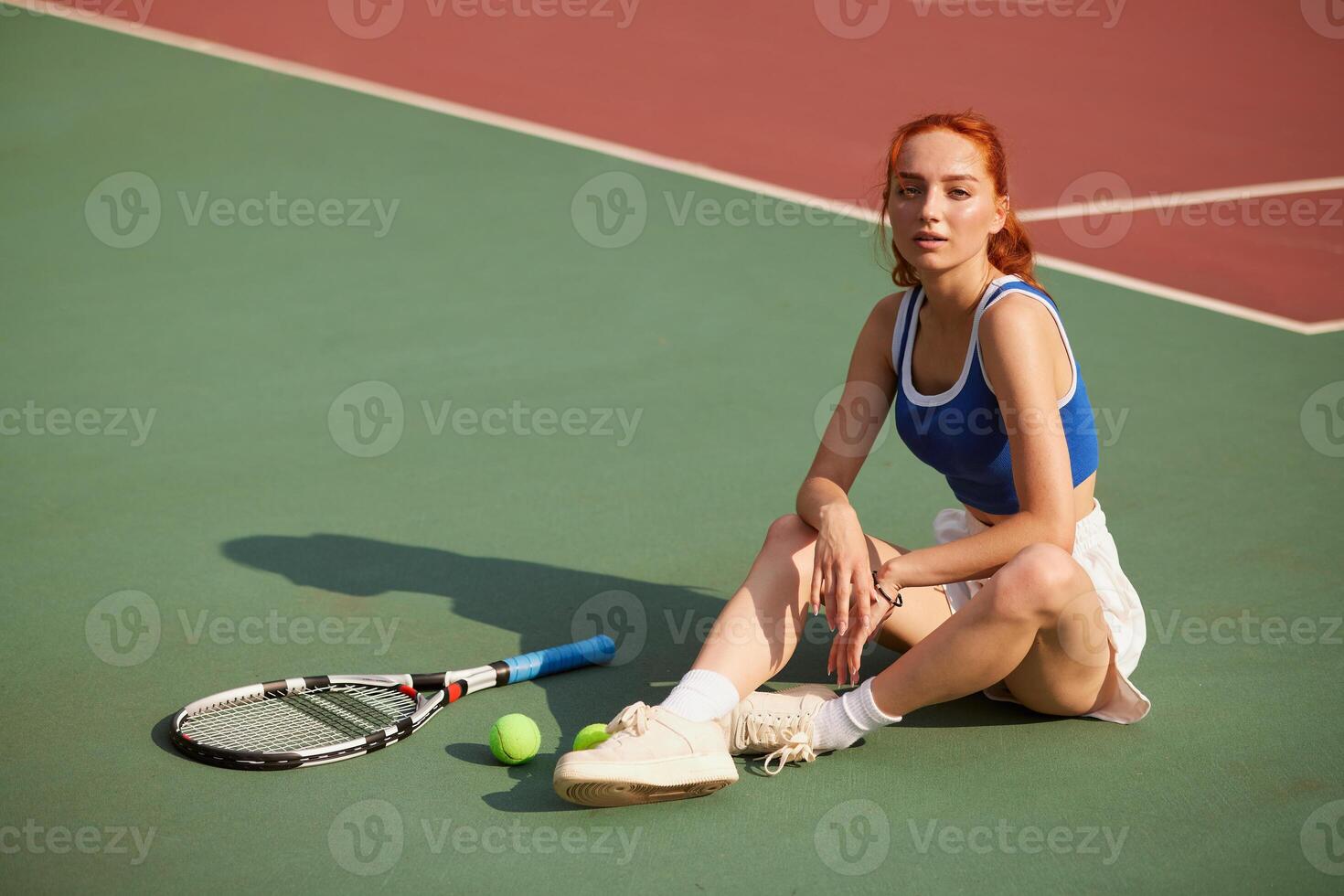 Young Female Tennis Player Resting on Court After Outdoor Practice with Racket and Balls in Summer Light photo