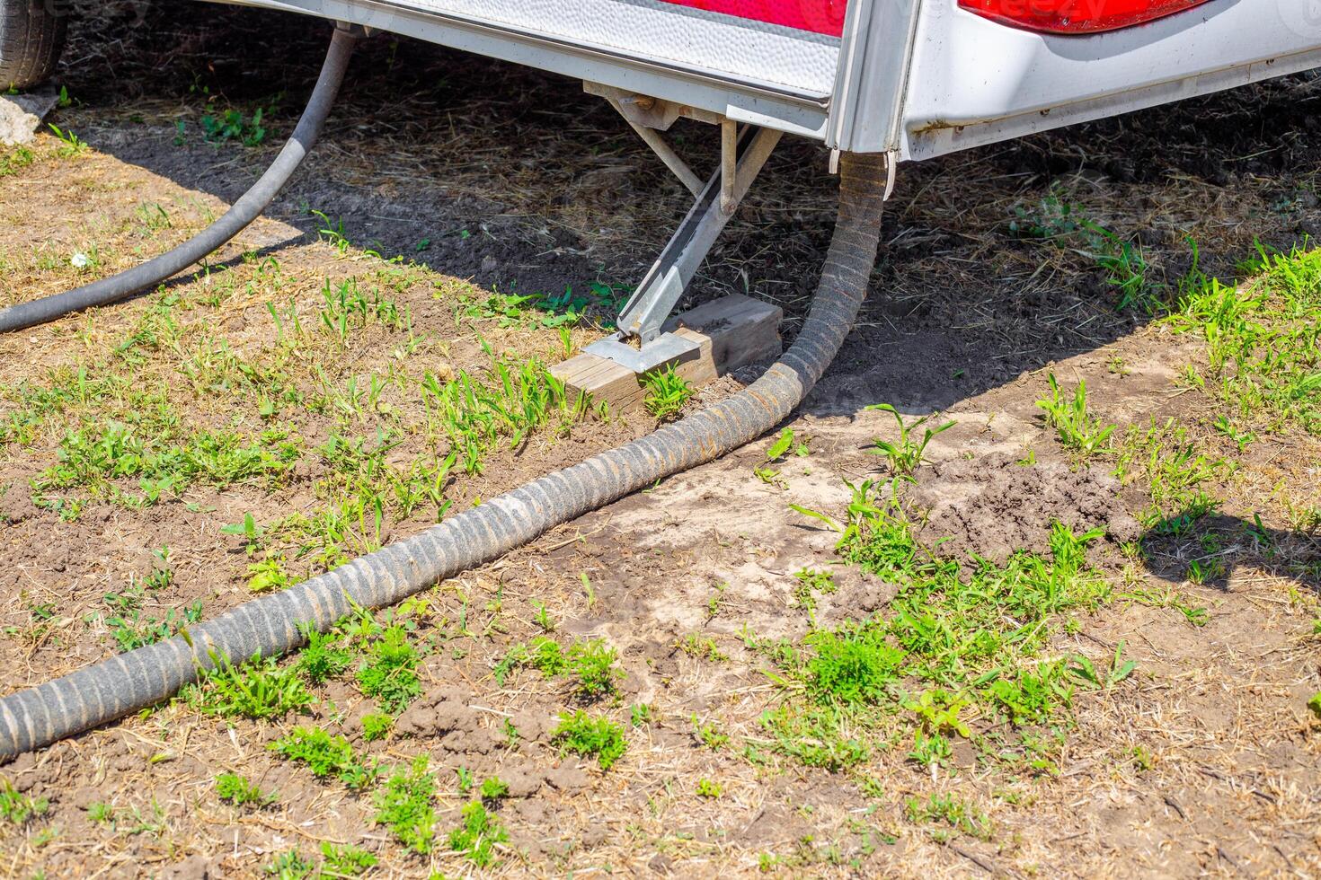 On the bottom of the camper, a connection between hoses and support structures on the ground. sewerage system photo