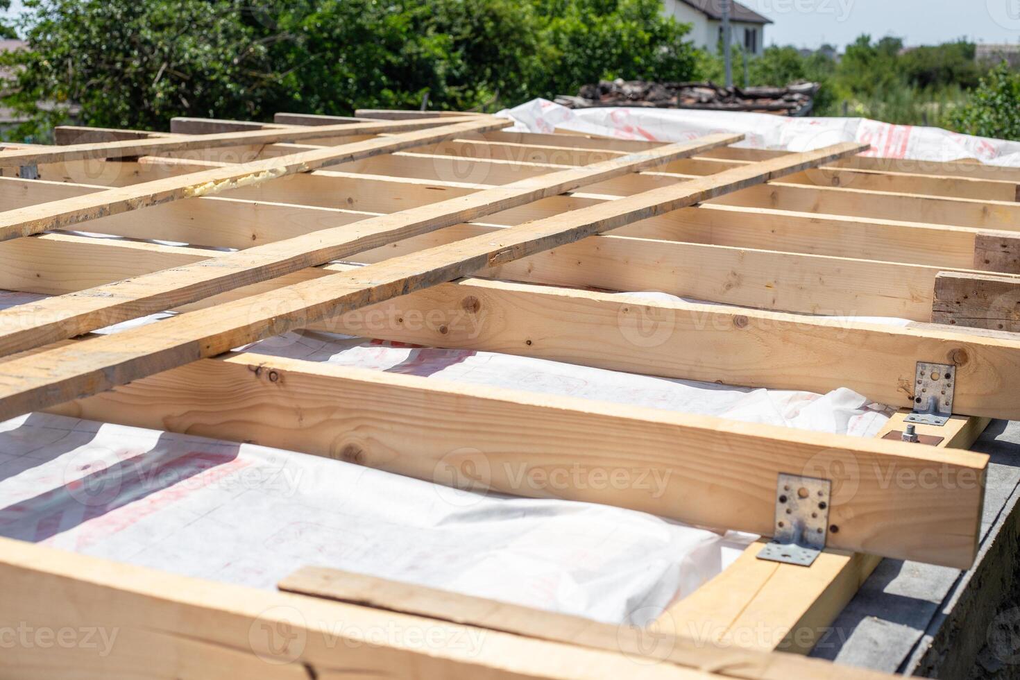 wooden roof frame under construction against rural landscape photo