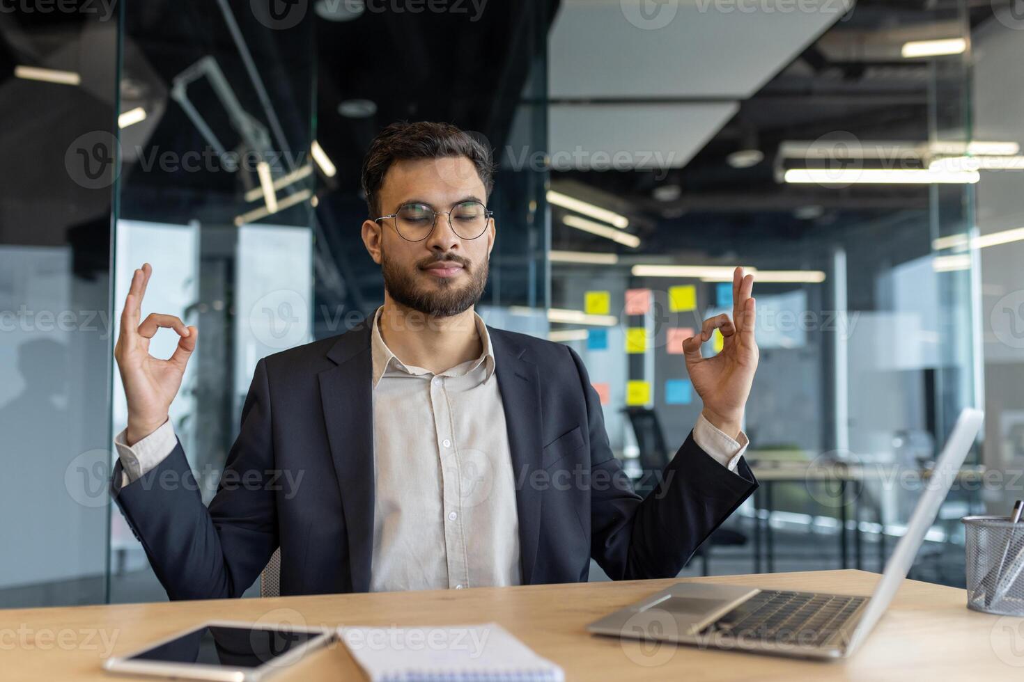 A businessman meditates in an office, showing relaxation and mindfulness for stress relief and work-life balance. photo