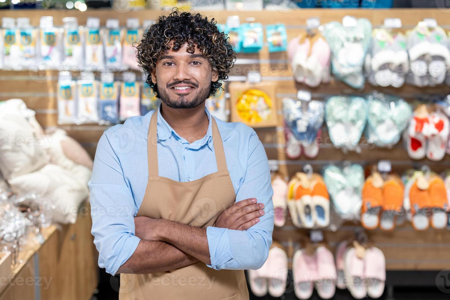 A smiling store employee with crossed arms in a retail environment, surrounded by various products on display. photo