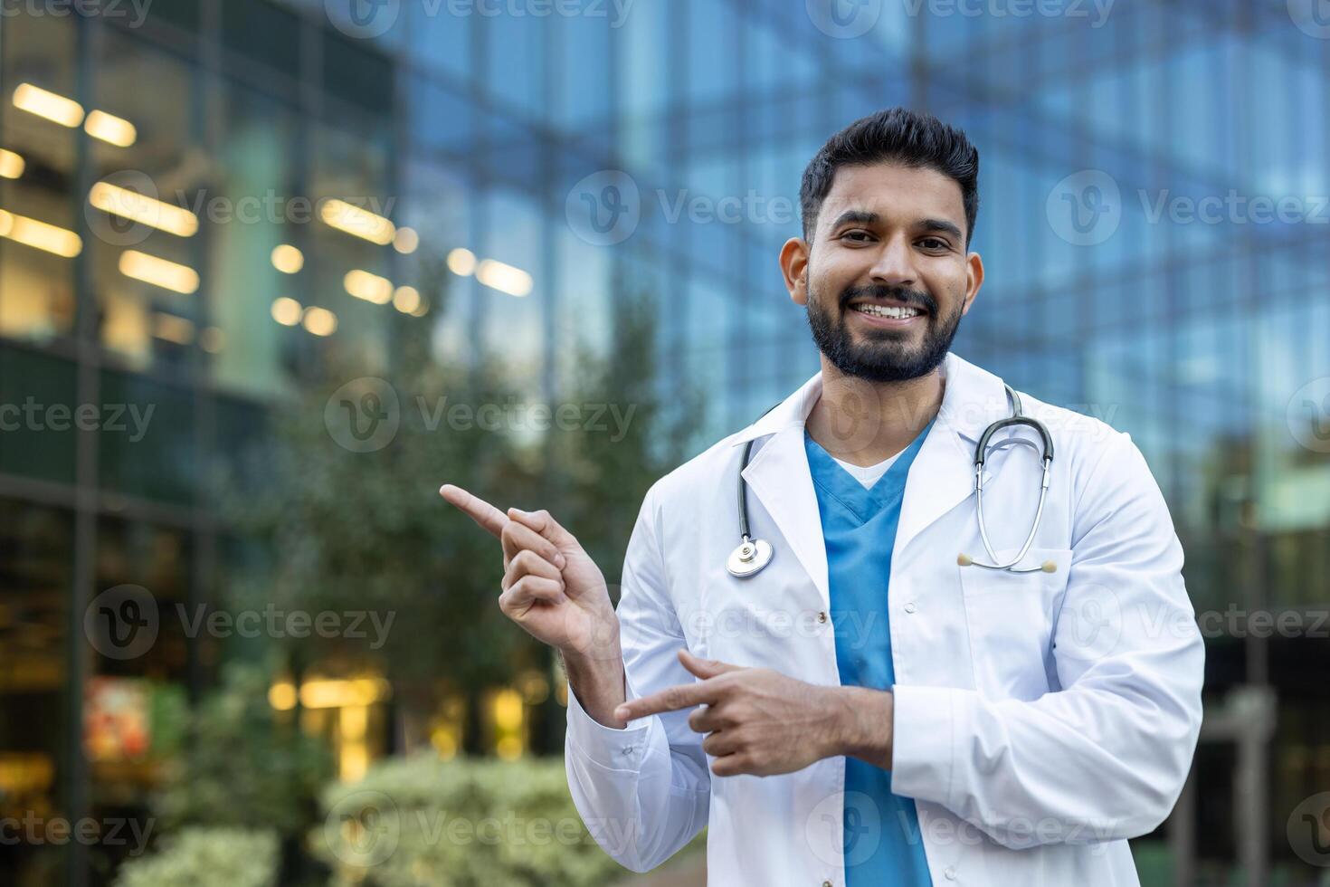 A smiling, Indian doctor points towards something with an urban background. photo