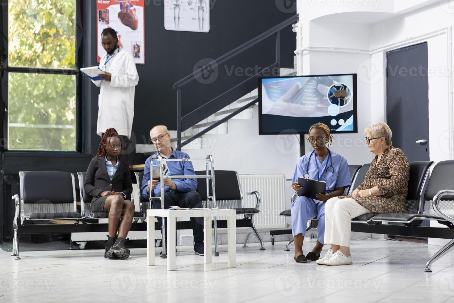 Black healthcare provider discussing with her patients in the hospital lobby, consulting and sharing advice in the waiting room at medical facility. African american nurse chatting with old woman. photo