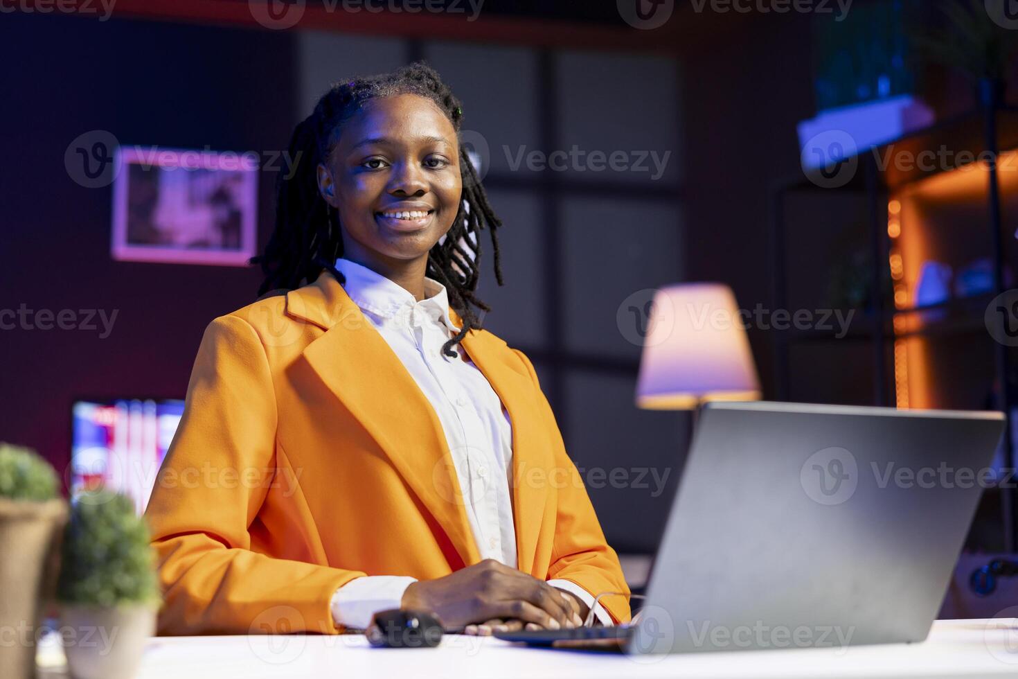 Portrait of smiling student at home browsing internet on notebook, doing homework, researching information online. Cheerful girl in apartment reading articles on laptop for school tasks photo