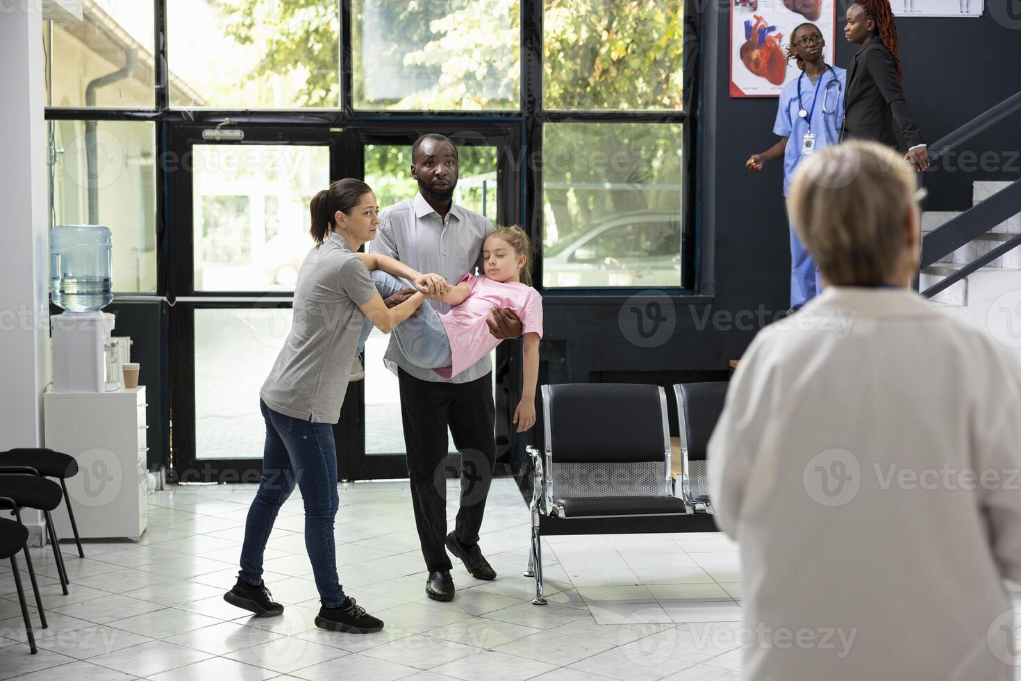 Diverse parents facing pediatric medical crisis after little girl collapses in lobby, asking for urgent support from black medical team in response to sudden panic and serious health scare. photo