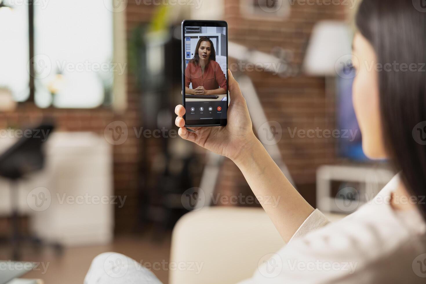 Remote employee sits on sofa, looking at digital device screen during online collaboration with white businesswoman. Female manager discussing marketing strategy with team member on call. photo
