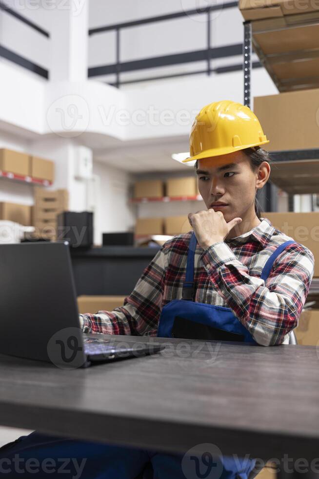 Asian employee sorting retail packages in a small fulfillment center, ensuring express delivery for a local brand. Staff handles order processing for growth in the depot, packaging station. photo