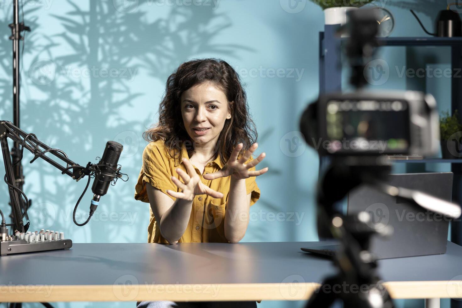 Enthusiastic internet show host hitting the record button on professional camera, using microphone to talk about today topic with subscribers. Media star filming creative vlog photo