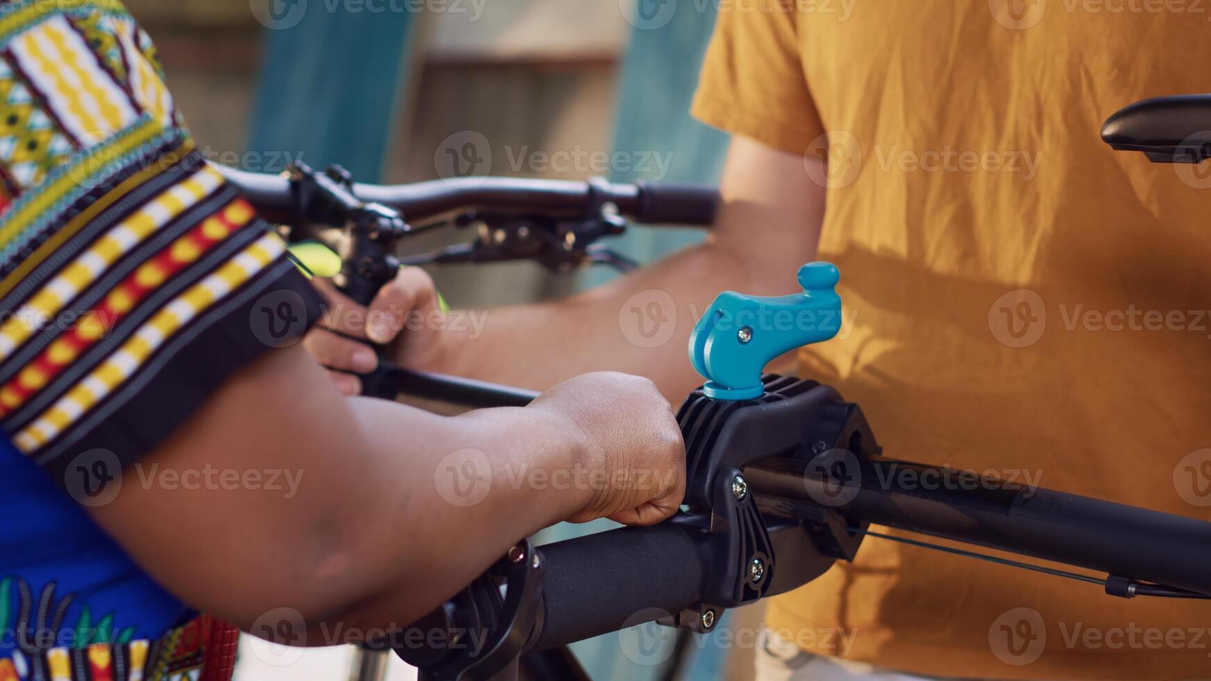 Detailed view showing people utilizing customized repair platform and tools to mend bicycle in backyard. Close-up shot of young diverse couple grabbing and clamping bike for fixing. photo