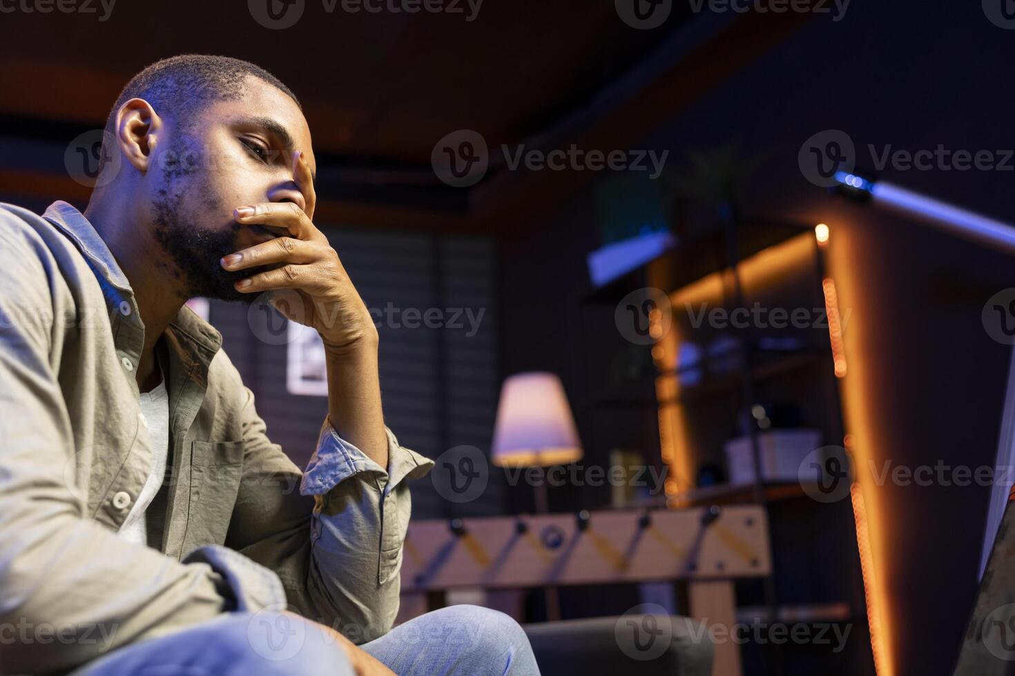 African american person receiving some bad news while doing remote work tasks, feeling overworked and under pressure to complete all his assignments. Young adult deals with burnout. photo