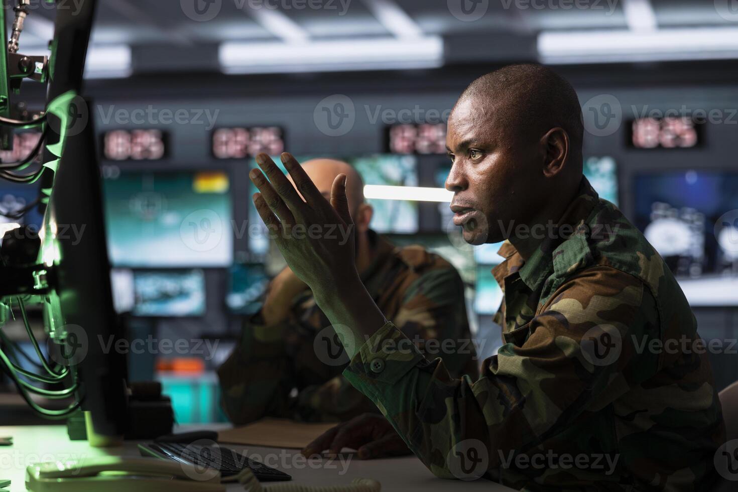 Military officer looking at surveillance monitor, analyzing data to allocate resources to units based on mission needs. African american agent examining strategic data on screen photo