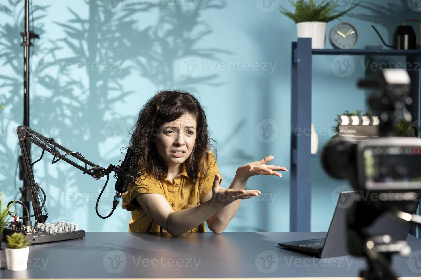 Woman doing live broadcast talking to audience about recent news headlines, feeling upset regarding concerning story, reading from laptop. Online show host complaining about info read on notebook photo