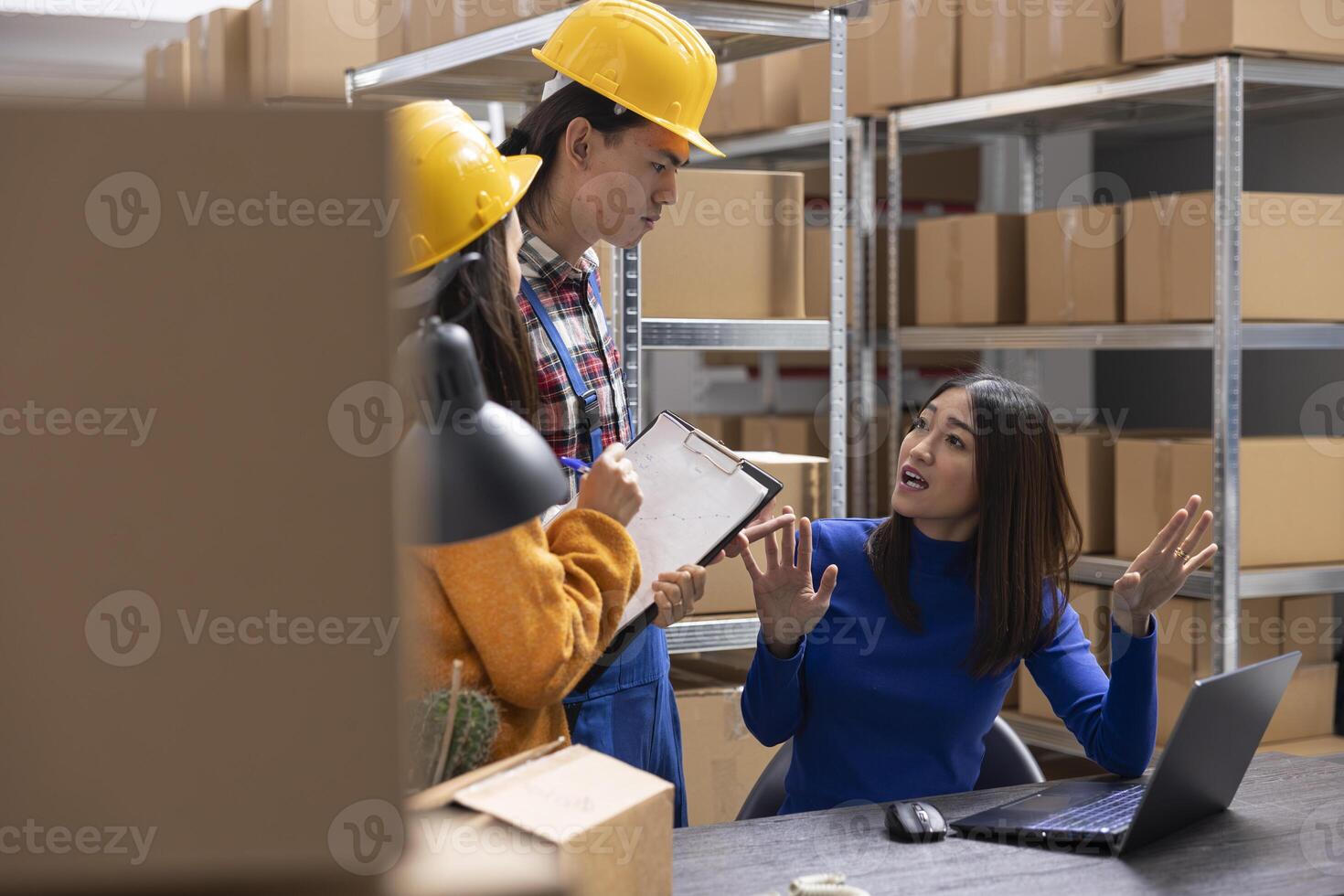 Asian staff preparing merchandise in boxes on shelving units at the depot of a local small business, small scale local brand. Team packing custom orders at the logistics center, local delivery. photo