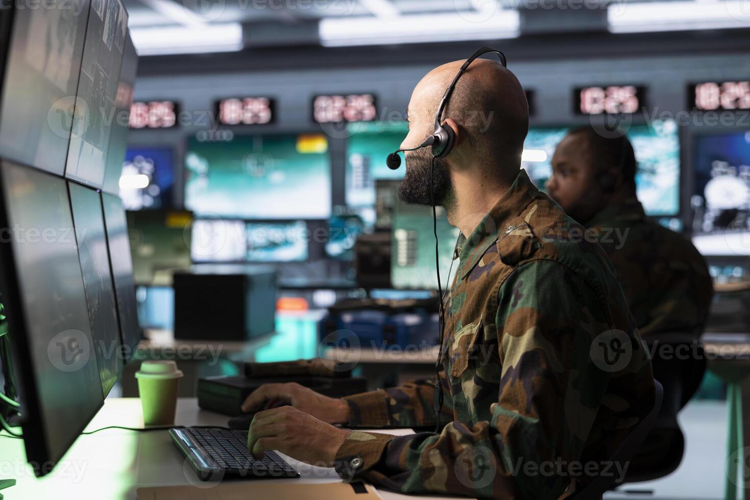 Military dispatcher in command post ready to respond to emergencies and communicate with soldiers on front lines. Middle Eastern war telecommunications operator in uniform talking in headset mic photo