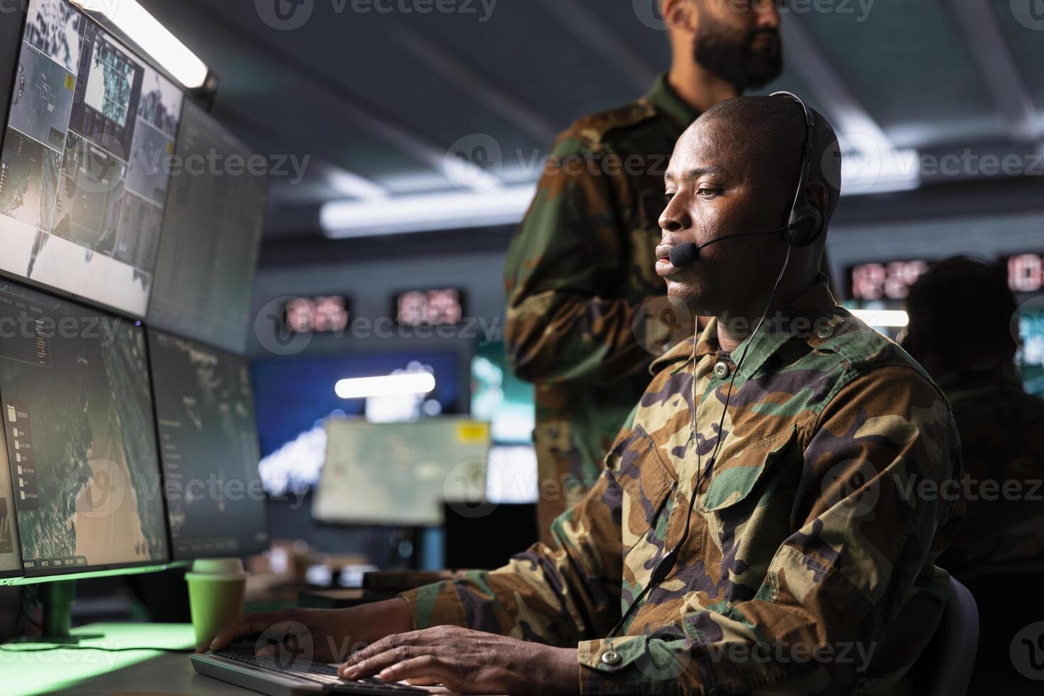 Counterintelligence agency dispatcher relays information from army intelligence analysts to front lines troops. African american radio communications operator in camouflage uniform talking in mic photo