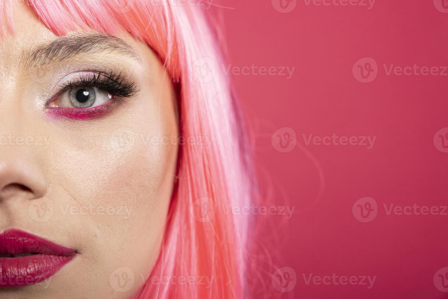 Closeup portrait of stunning woman, only half of her face visible as she looks confidently into the lens. Elegant female exuding confidence and grace with pink background emphasizing facial features. photo