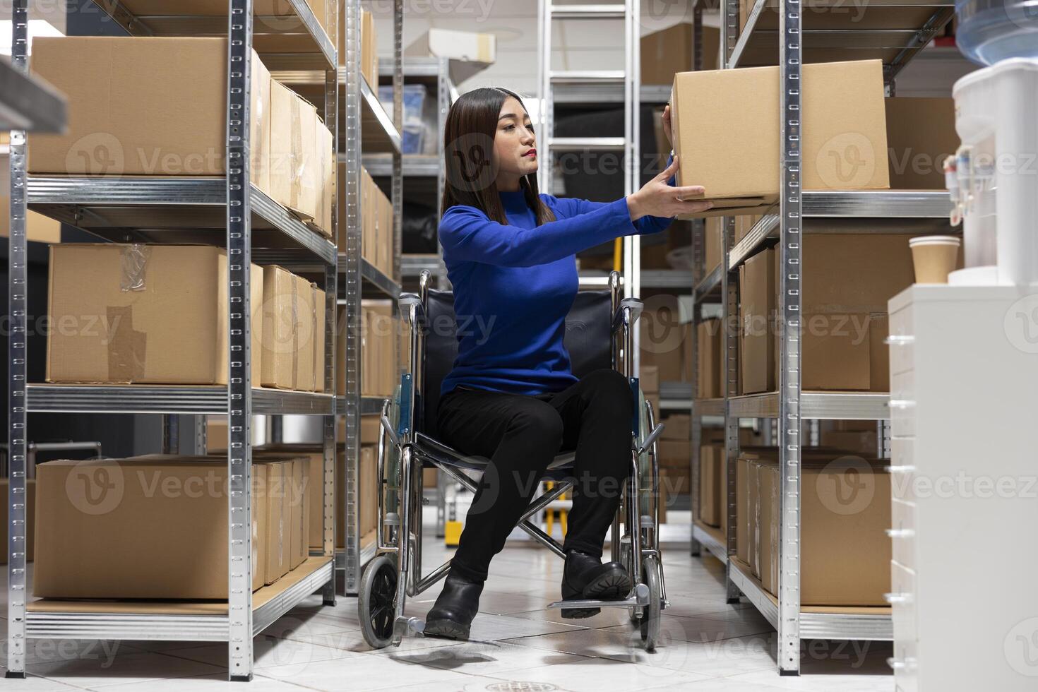 Asian woman with reduced mobility checking packages for custom orders, distribution hub focusing on retail operations for the small business. Accessible inclusive workspace with goods. photo
