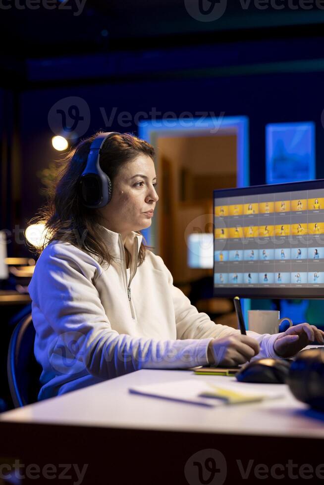 Photographer wearing headphones using retouching program on graphic tablet to edit images. Teleworking photo editor hearing podcasts while doing color grading on photographs in home studio