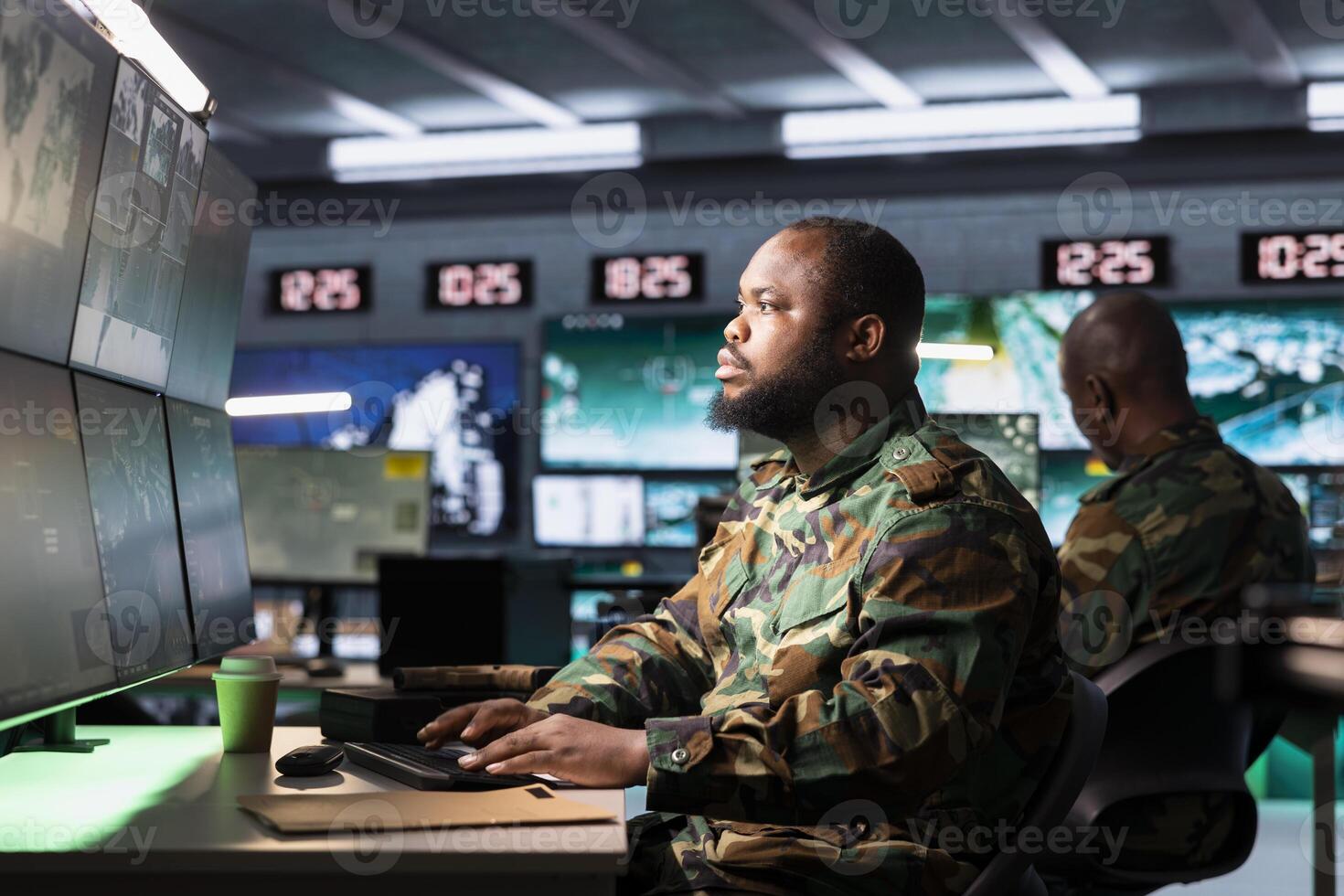 Soldier in war room analyzing aerial reconnaissance data to come up with warfare winning tactics. African american intelligence agency agent controlling drones attacking strategic targets photo