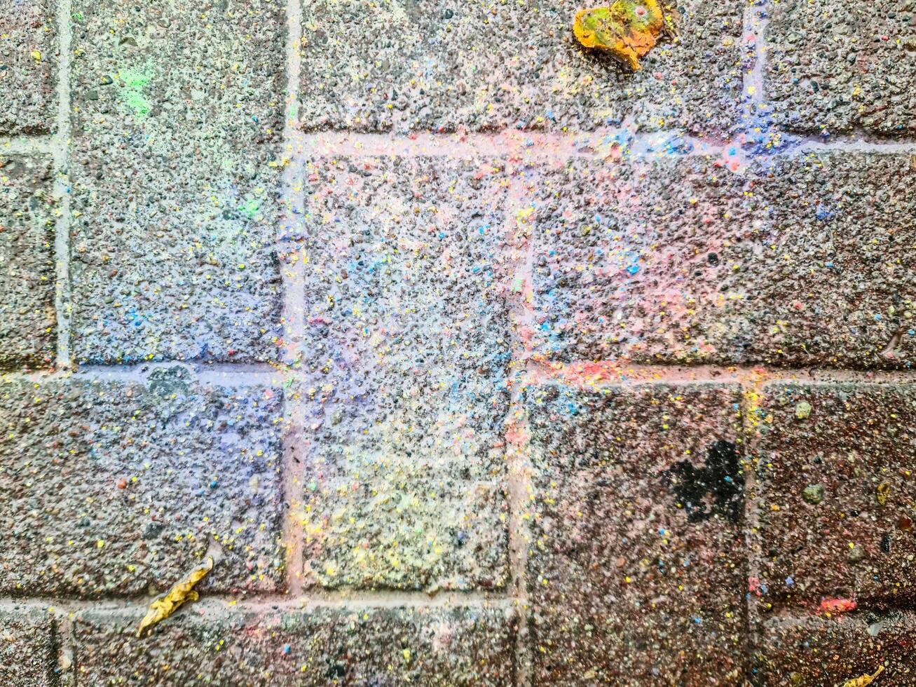 Colorful paint splattered on a brick wall creating an abstract pattern photo
