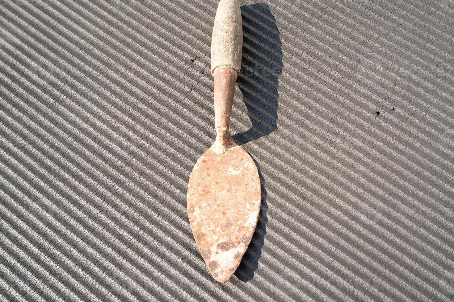 A rusty trowel with a wooden handle isolated on black backgrounds. Hand shovel used for planting plants in pots or digging soil. Tool and equipment for gardening . Graphic resources. Copy space photo