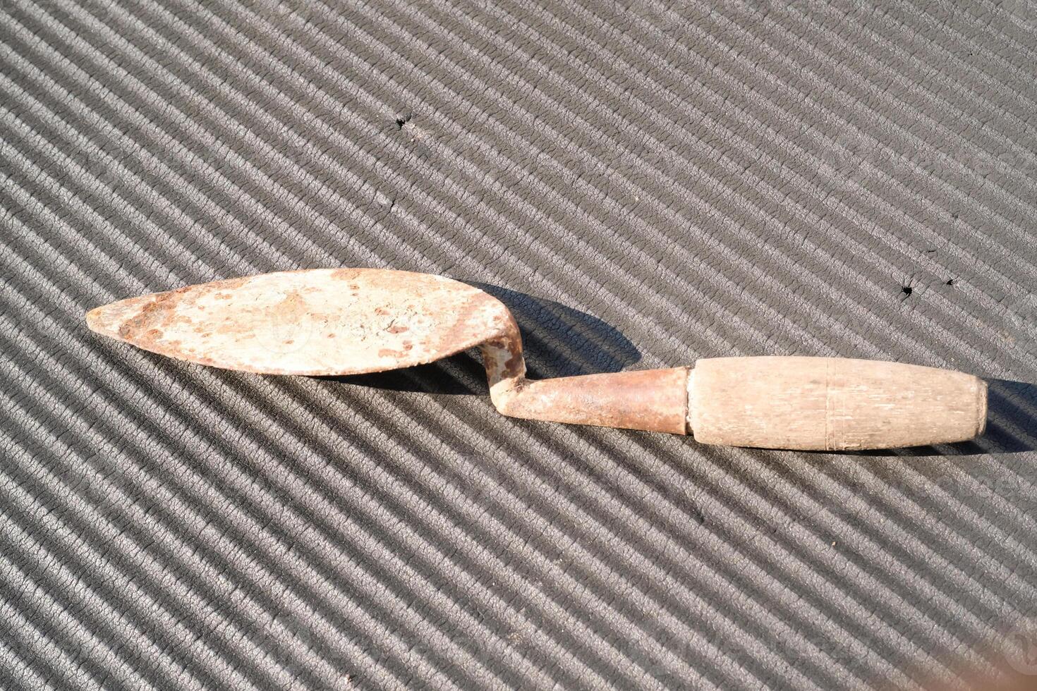 A rusty trowel with a wooden handle isolated on black backgrounds. Hand shovel used for planting plants in pots or digging soil. Tool and equipment for gardening . Graphic resources. Negative space photo