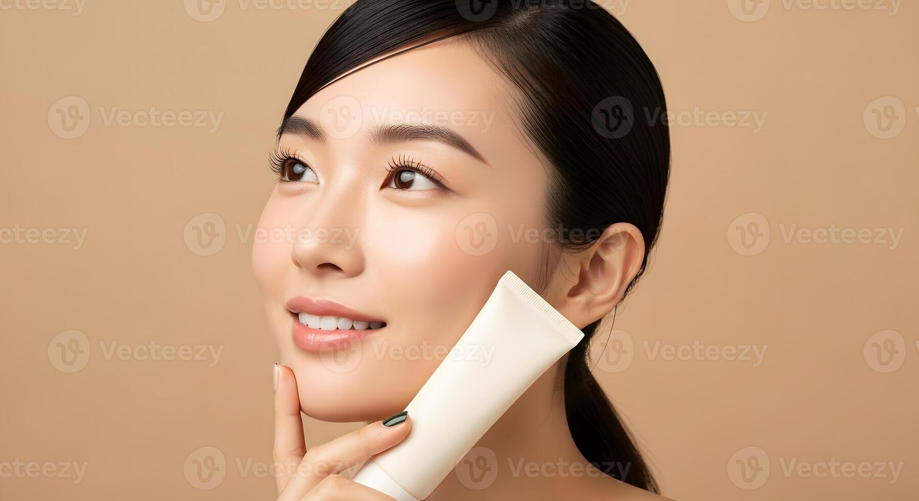 Radiant Asian Woman Promoting Beauty Product, Close-up Beauty Shot of a Smiling Woman with Flawless Skin and a Tube of Cream photo