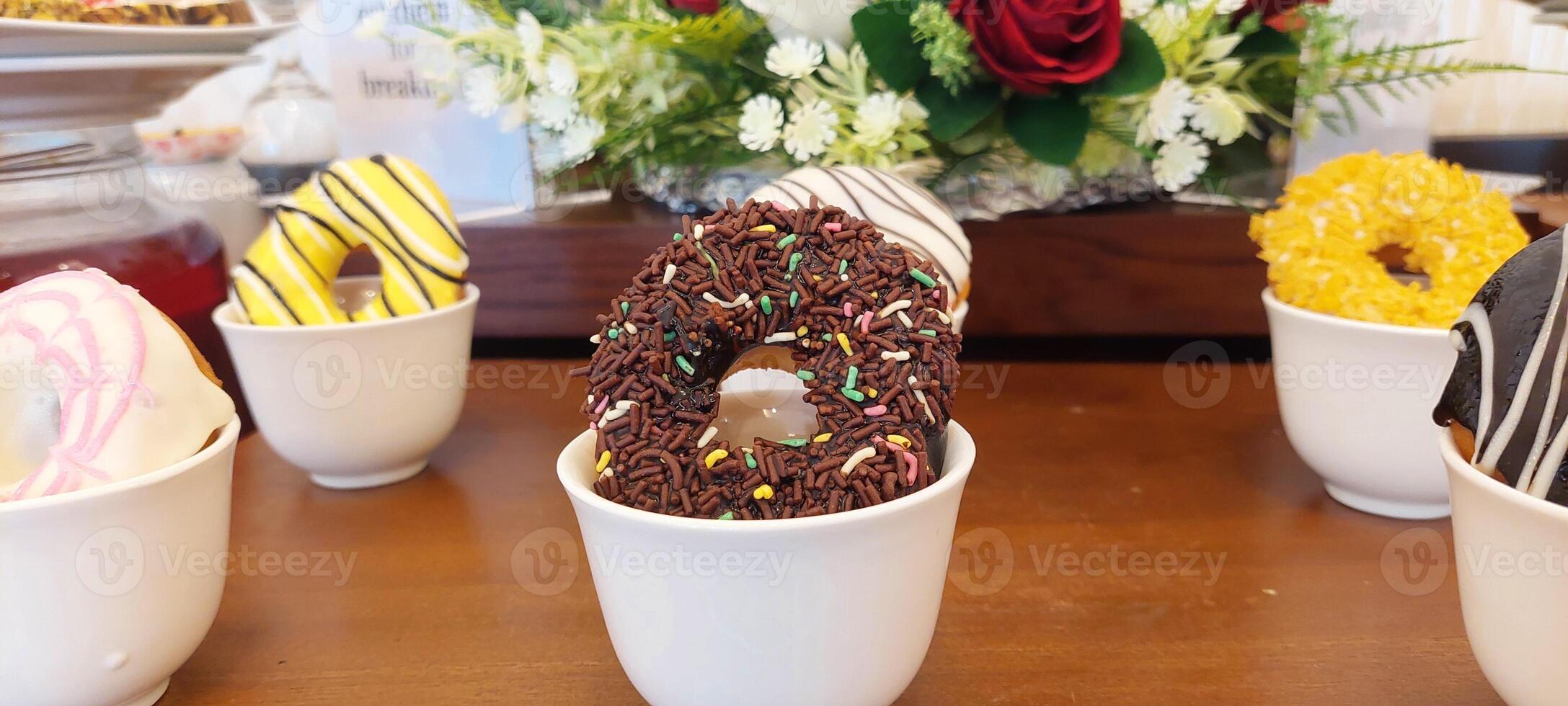 A table with several cups of donuts and a vase of flowers photo