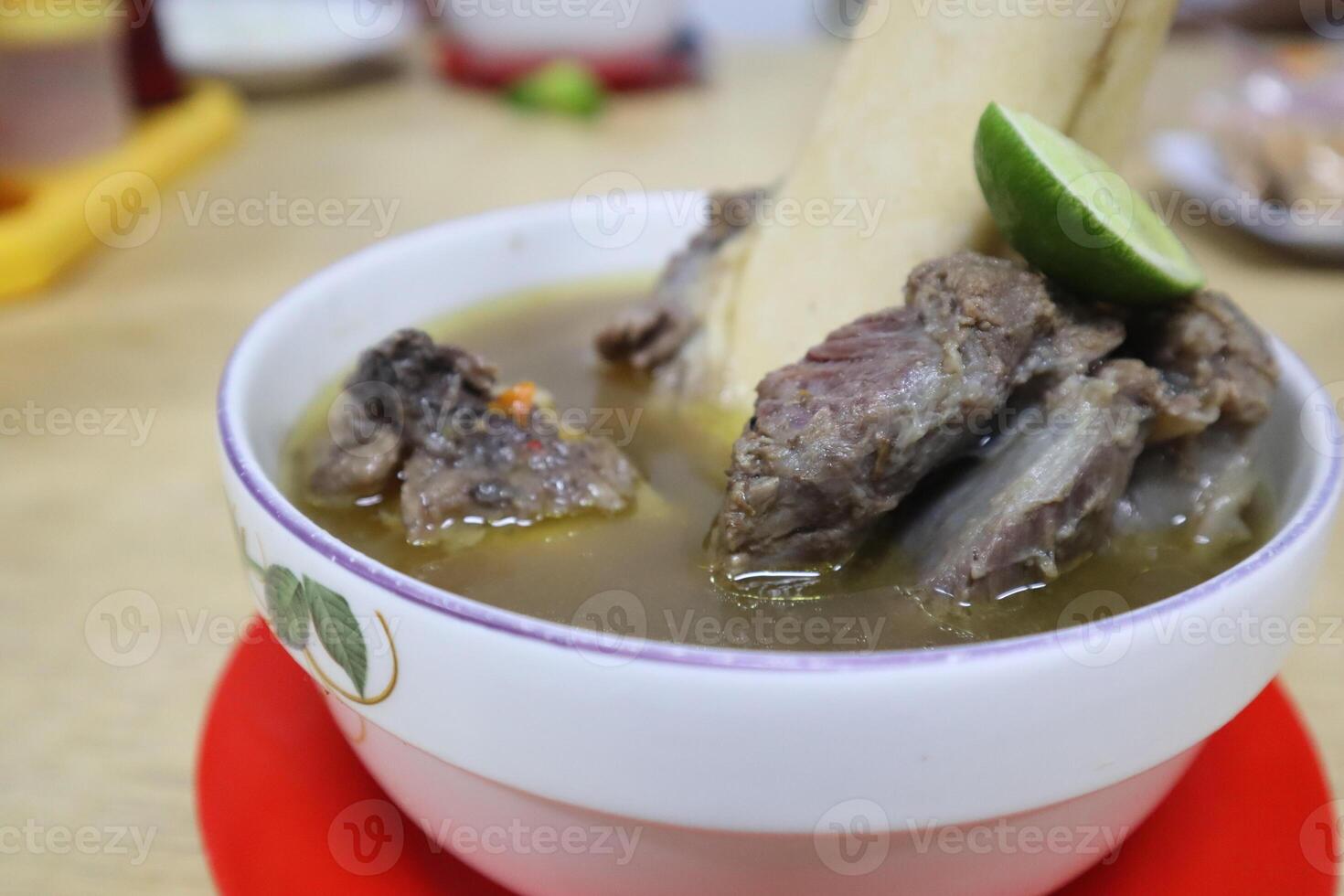 A bowl of soup with meat and a stick photo