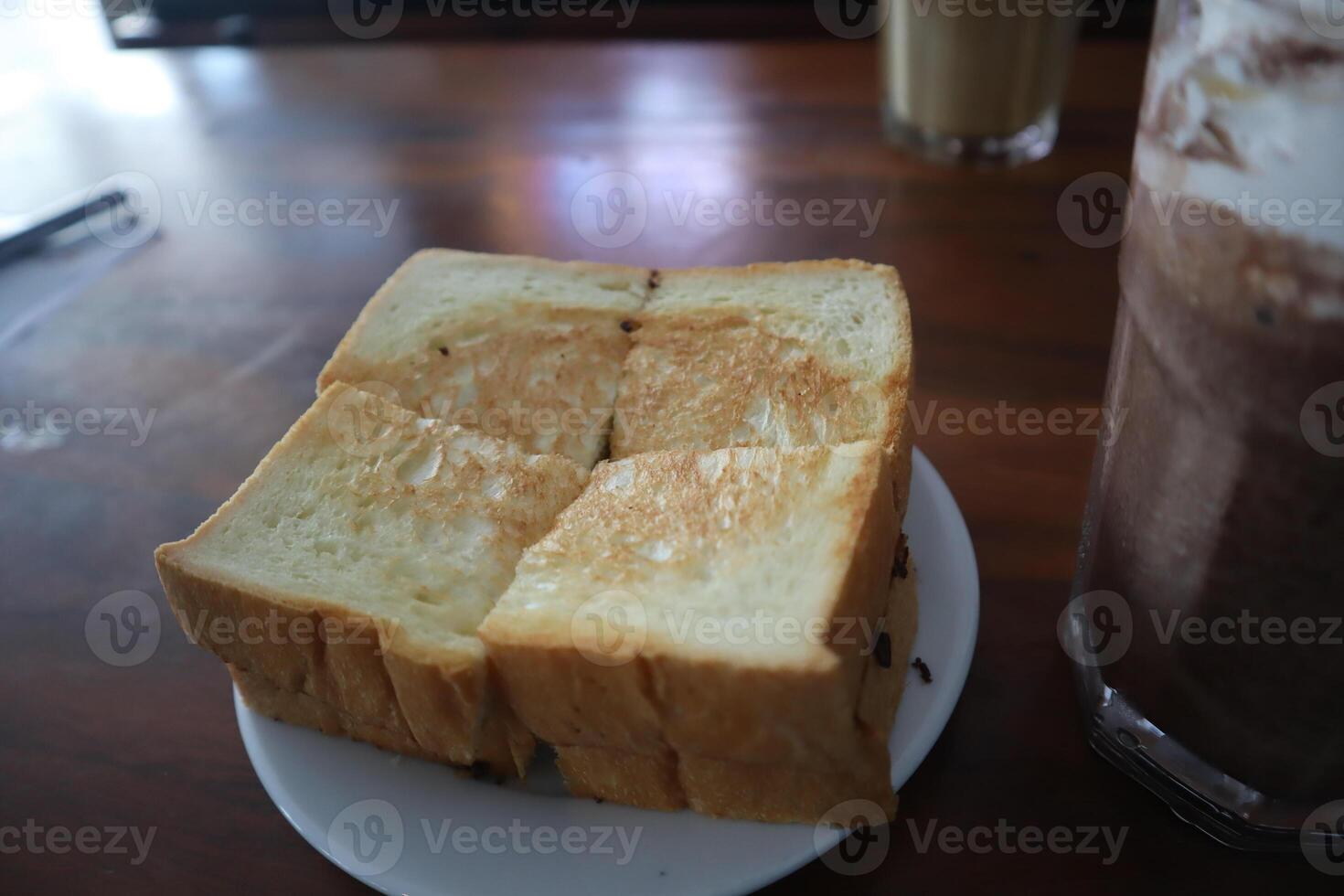 A piece of toast on a plate next to a drink photo