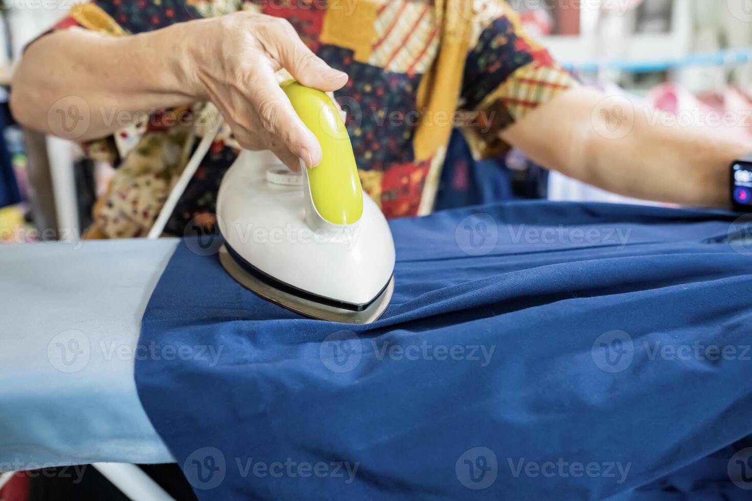 Senior citizens ironing student skirt and clothing in a house.a photo