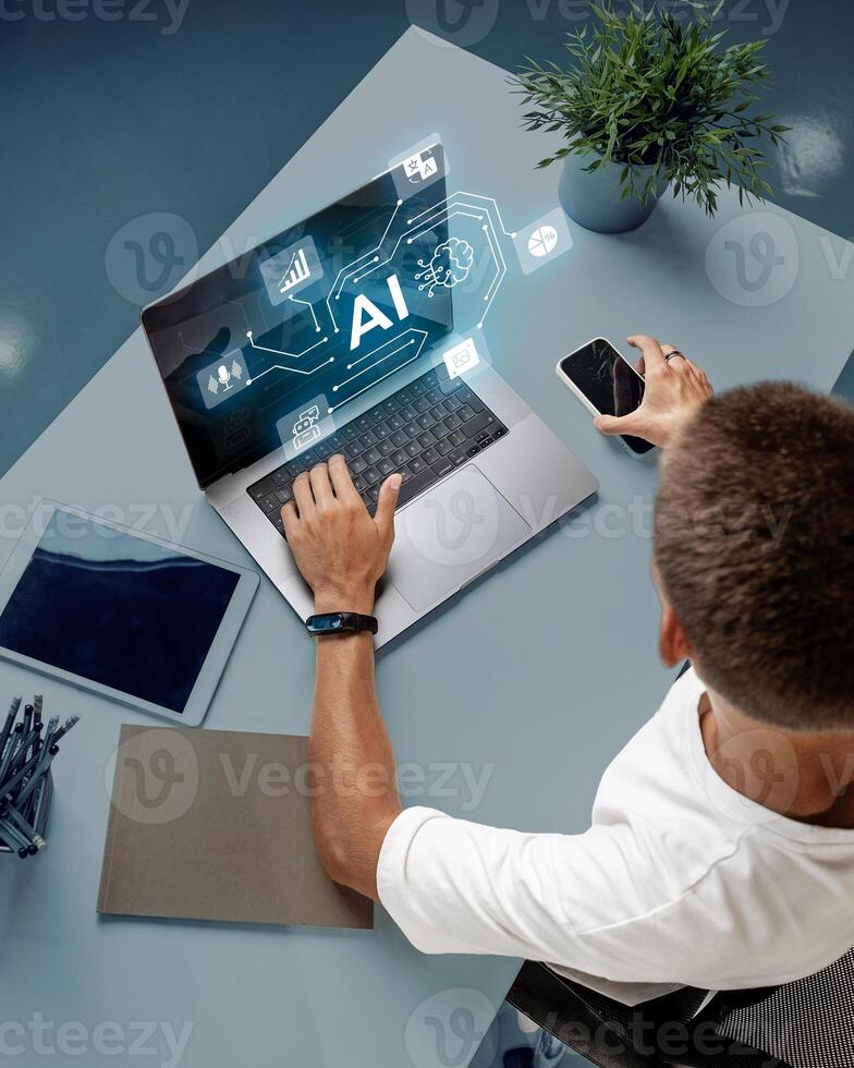 Young professional engages with AI technology on laptop while using smartphone in modern office setting during daytime photo