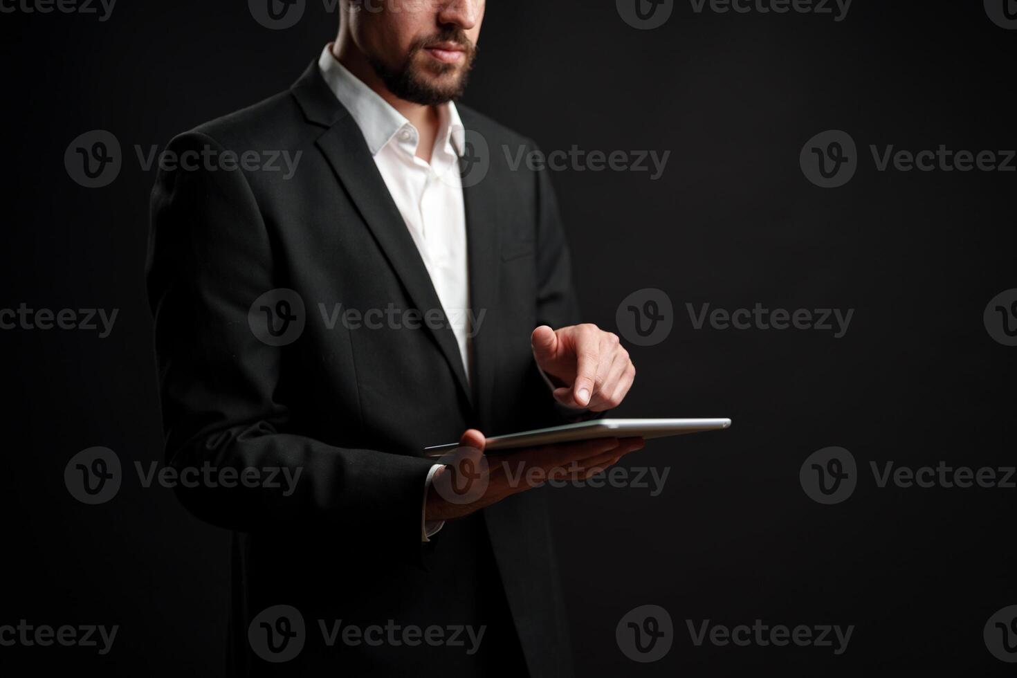Business professional interacts with tablet in studio setting against dark background photo