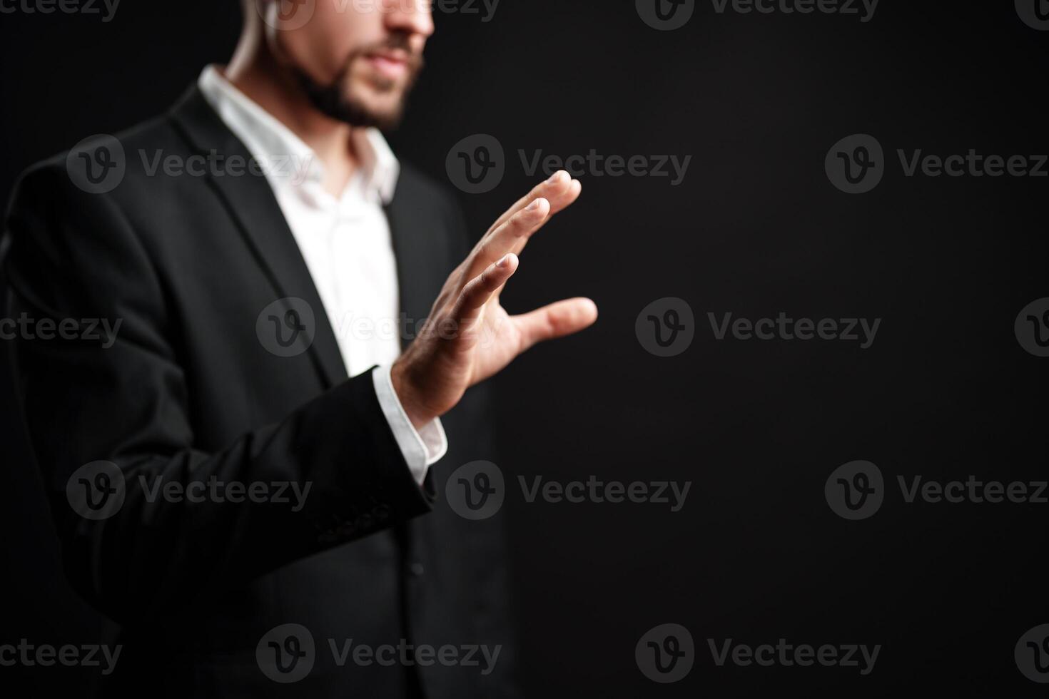 Professional man gesturing with hand against dark background in a corporate setting during afternoon hours photo