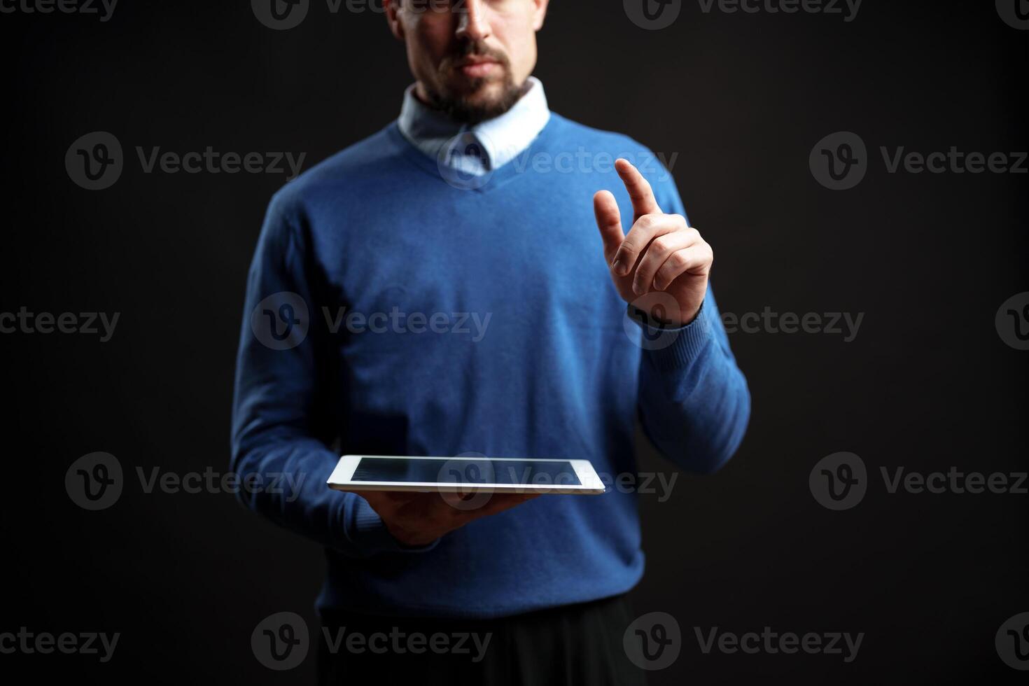 Professional man interacts with tablet in a dark studio setting during a digital presentation photo
