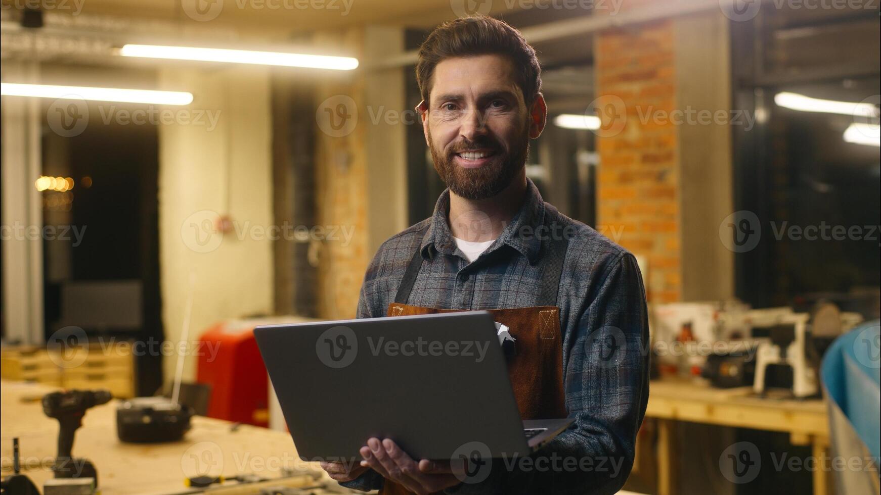 Positive Caucasian wood master man typing laptop online in workshop small business craftsman guy using computer device male joiner worker smile carpenter virtual shopping application Internet website photo