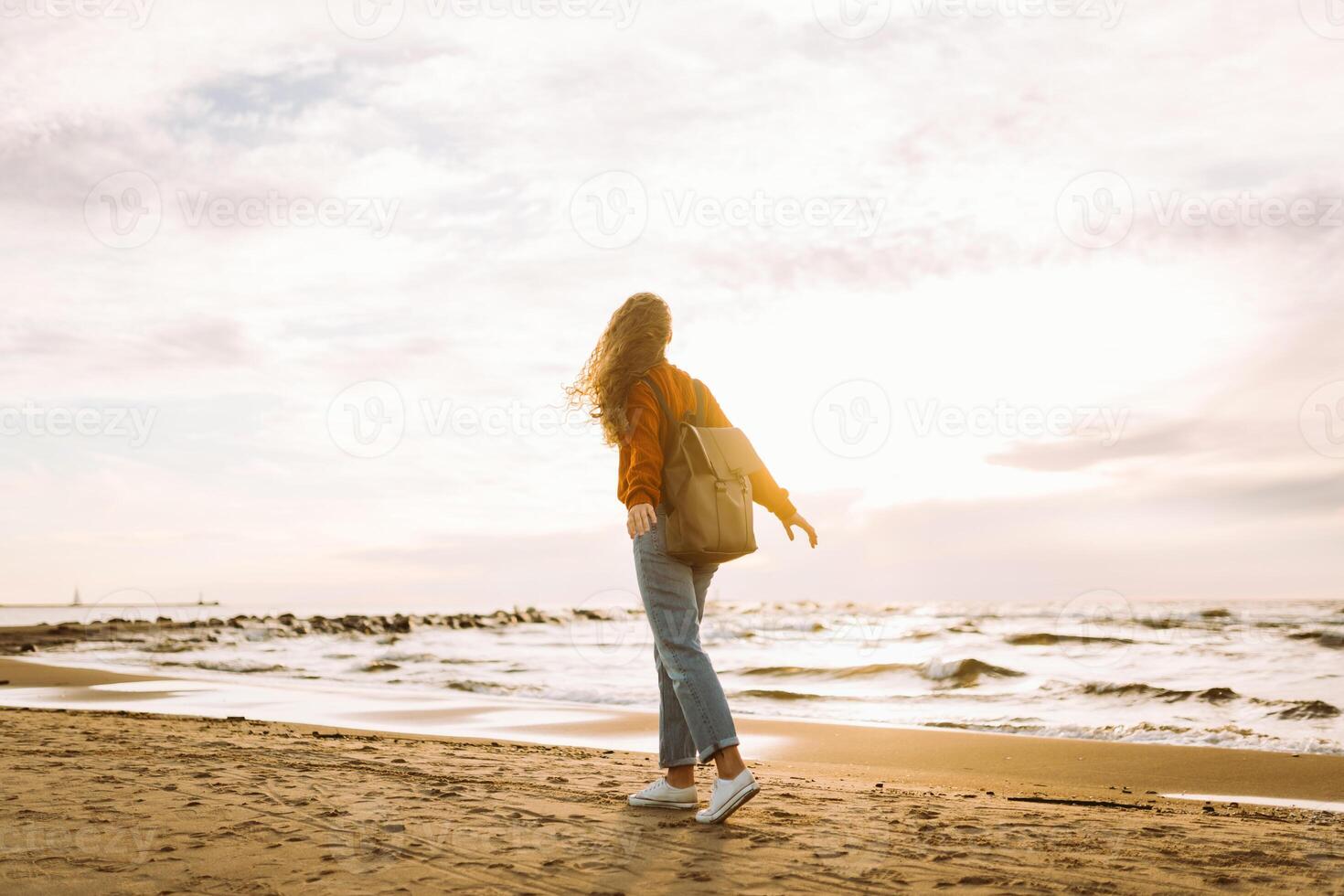Woman enjoying breezy near vibrant red lighthouse at sunset. Travel, weekend, lifestyle concept. photo