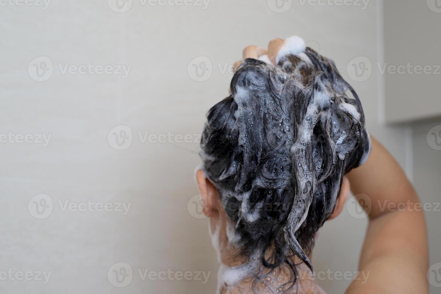 A woman is taking a shower and washing her hair in the b photo