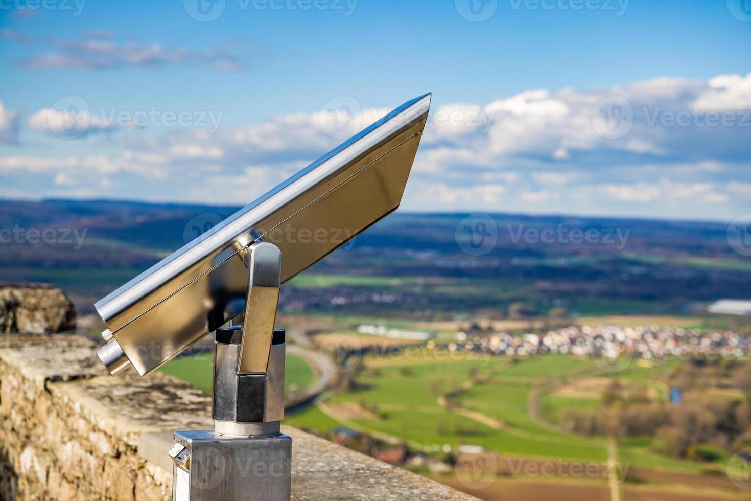 A telescope is located on the observation deck of the Hohenwil castle overlooking the city of Singen and cloudy sky photo