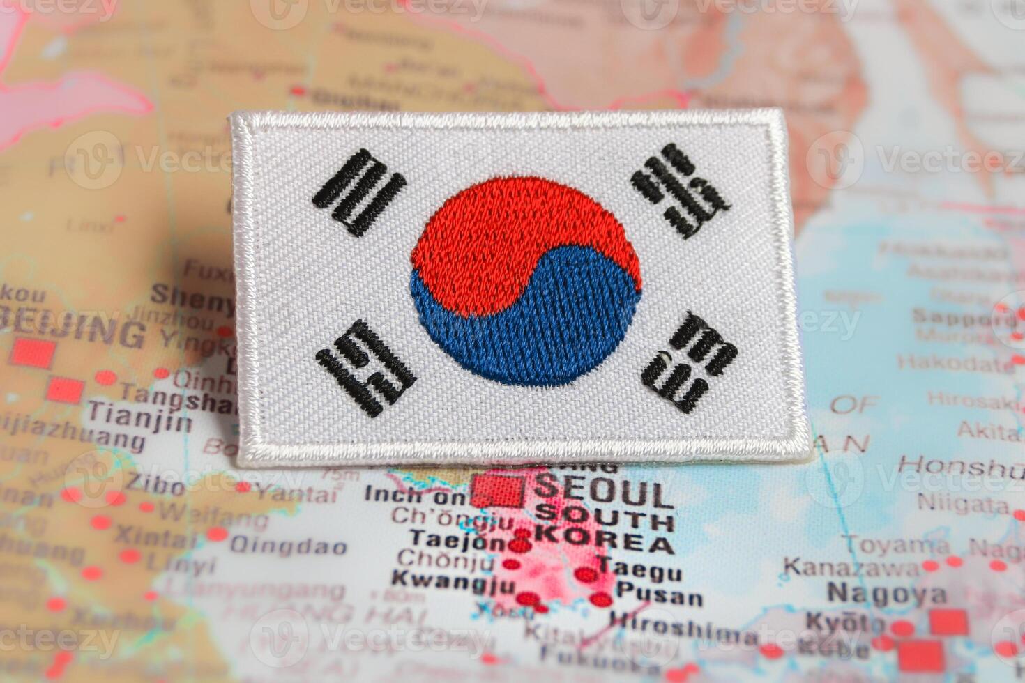 Horizontal shot of South Korea national flag KR flag embroidered with thread, placed on world map at Seoul South Korea. Symbol of travel, patriotism and culture. photo