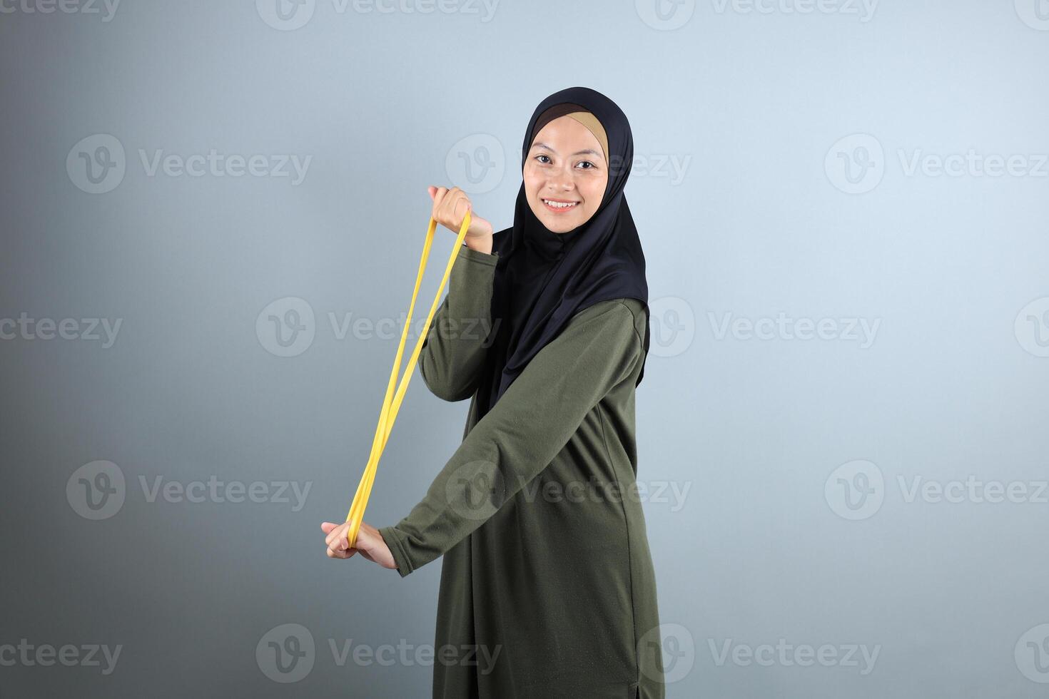 Young Asian Hijab Woman Stretch Yellow Resistance Band for Hand Pilates Exercise Sport photo